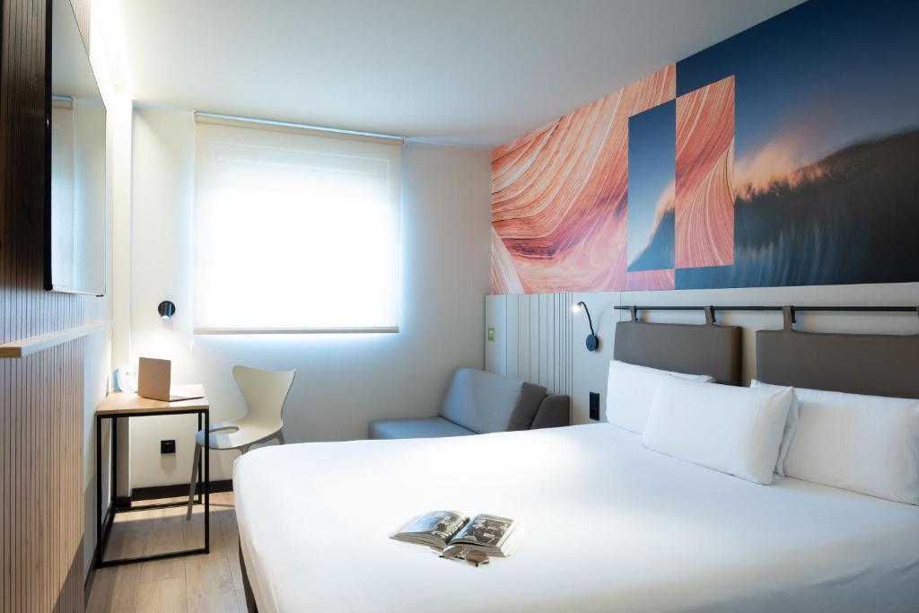 Un dormitorio con una gran cama blanca y una silla. en ibis Styles Santander, en Santander