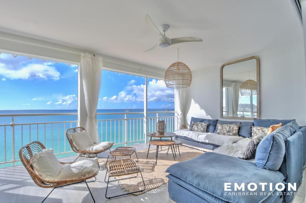 a living room with a blue couch and chairs at Appartement 2 chambres sur la plage de grand case in Grand Case