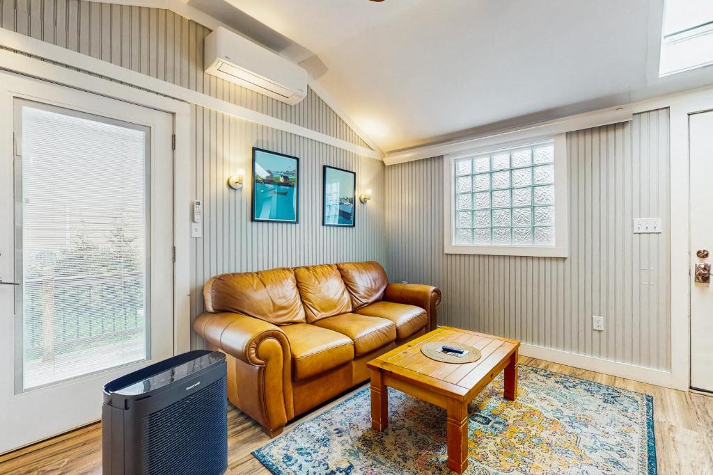 a living room with a leather couch and a table at Shorelands Resort Cottage 40 in Kennebunk