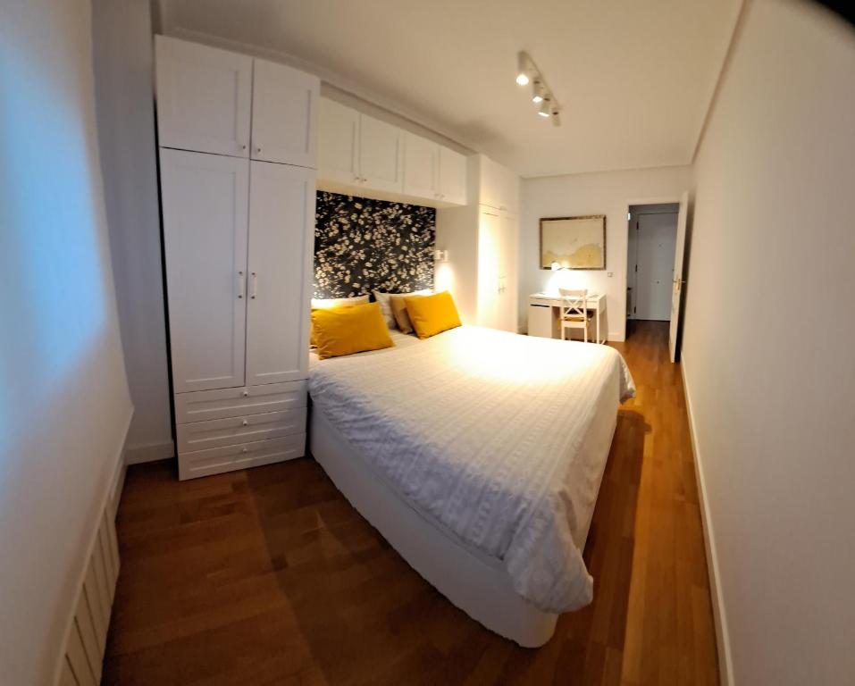 a bedroom with a large white bed with yellow pillows at Luminoso y Azul VUT 4654 AS in Avilés