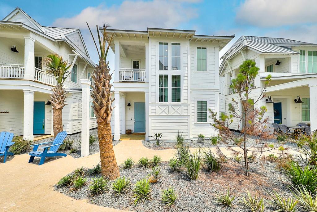 a large white house with blue chairs and a palm tree at Vida del Mar in Mustang Beach