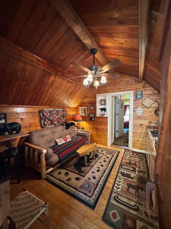 a living room with a couch and a ceiling fan at Big Bear Log cabin in Cosby