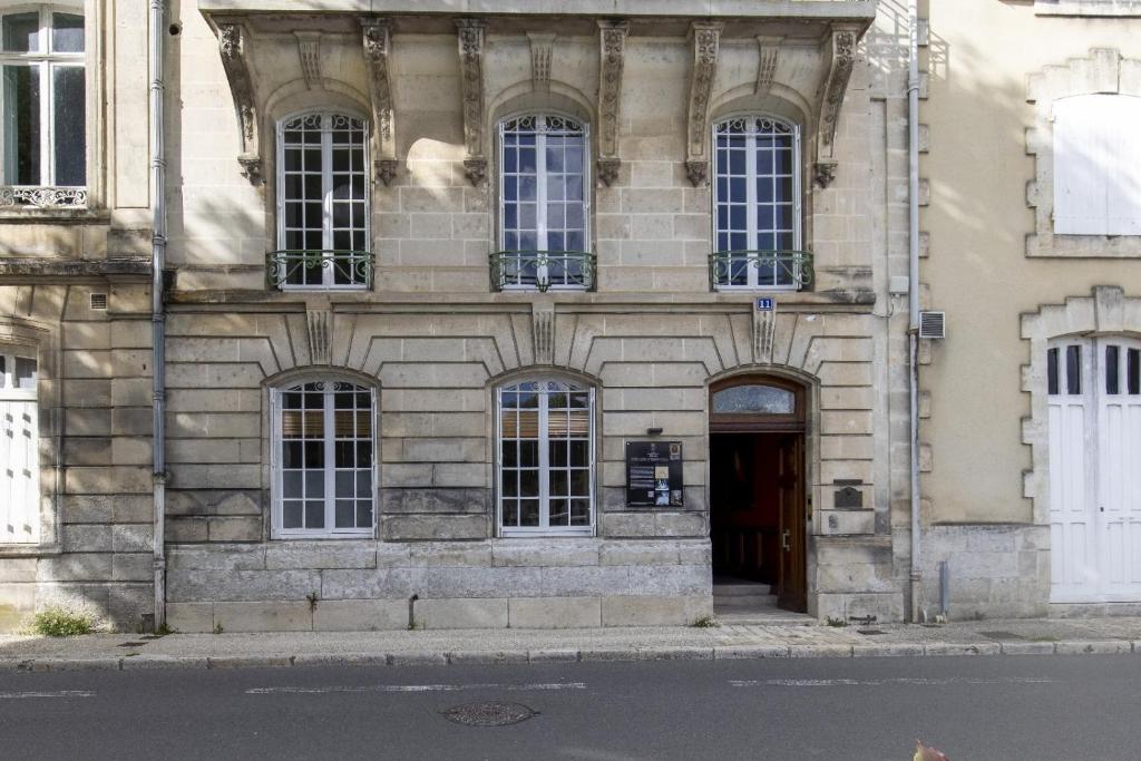 an old stone building with a door and windows at Les appartements de l'Orangerie in Jarnac