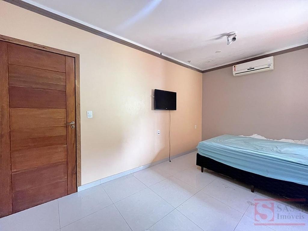 a bedroom with a bed and a door and a television at Pousada Miriam in Limeira
