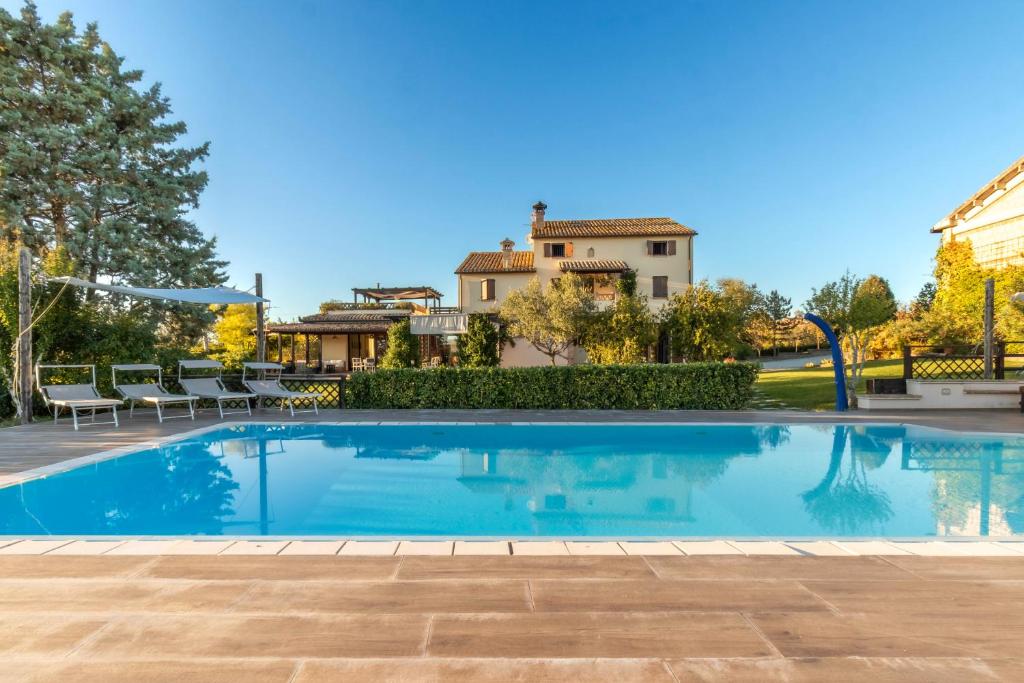 a swimming pool in a yard with a house in the background at Country House Binnella in Cingoli