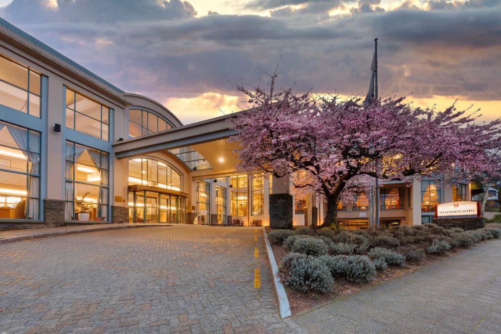 a building with a flowering tree in front of it at Millennium Hotel Queenstown in Queenstown