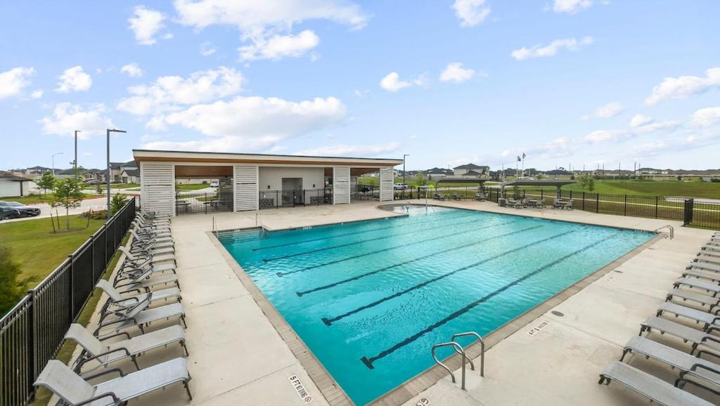 a large swimming pool with chairs around it at The Evergreen Escape in Rosenberg