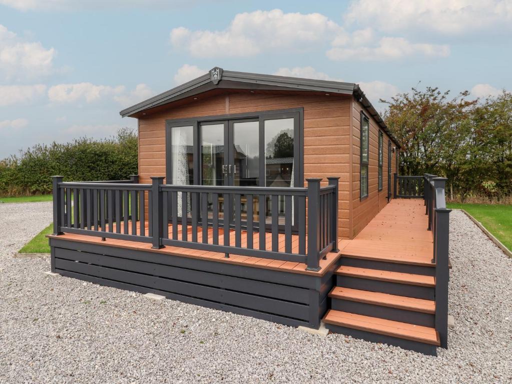 a tiny house with a large deck and stairs at Meadows Park 3 in Hull