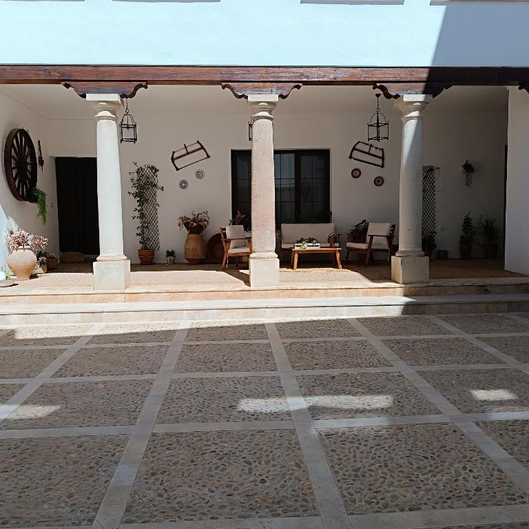 a courtyard with a building with pillars and chairs at La Fragua de Domingo in Villanueva de los Infantes