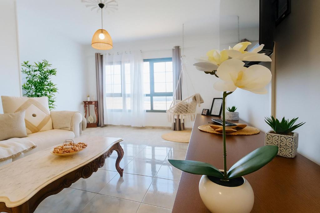 een woonkamer met een tafel en een bloem in een vaas bij K'Laya Life Beach A in Arinaga