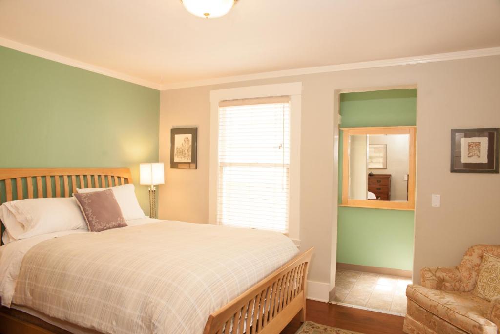 een slaapkamer met een bed, een stoel en een raam bij Chapala Gardens Historic West Beach 1BR - Unit 2 in Santa Barbara