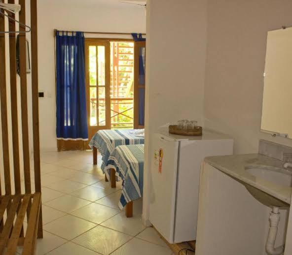 a kitchen with a refrigerator and a sink and a table at Pousada Praia da Pipa in Pipa