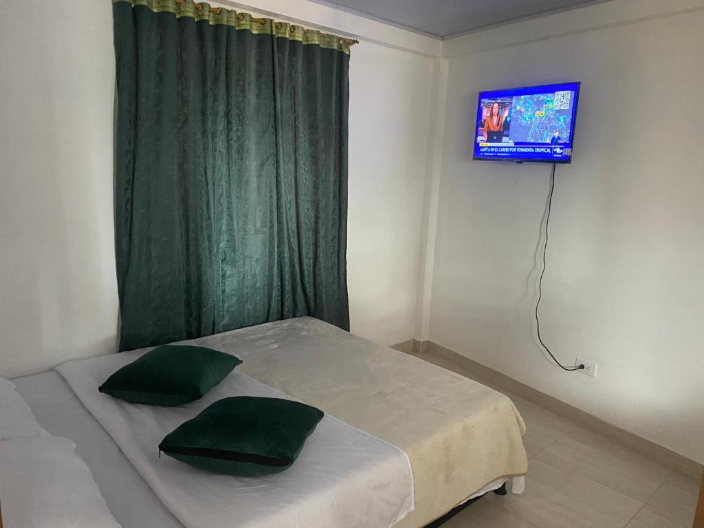 een slaapkamer met een bed met groene gordijnen en een televisie bij La bendición de sunnyvale cabaña pequeña 4 personas in La Vega