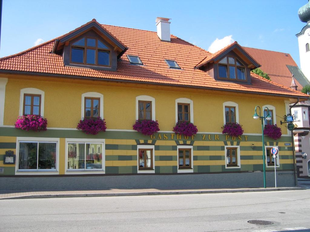 un bâtiment jaune avec des fleurs sur son côté dans l'établissement Gasthof zur Post, à Schörfling