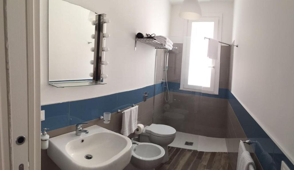 un bagno con lavandino, water e specchio di Le Cale Camera Privata in Residence a Favignana