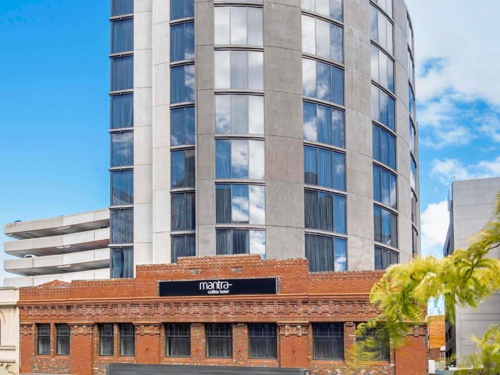a tall building in front of a brick building at Mantra Collins Hotel in Hobart