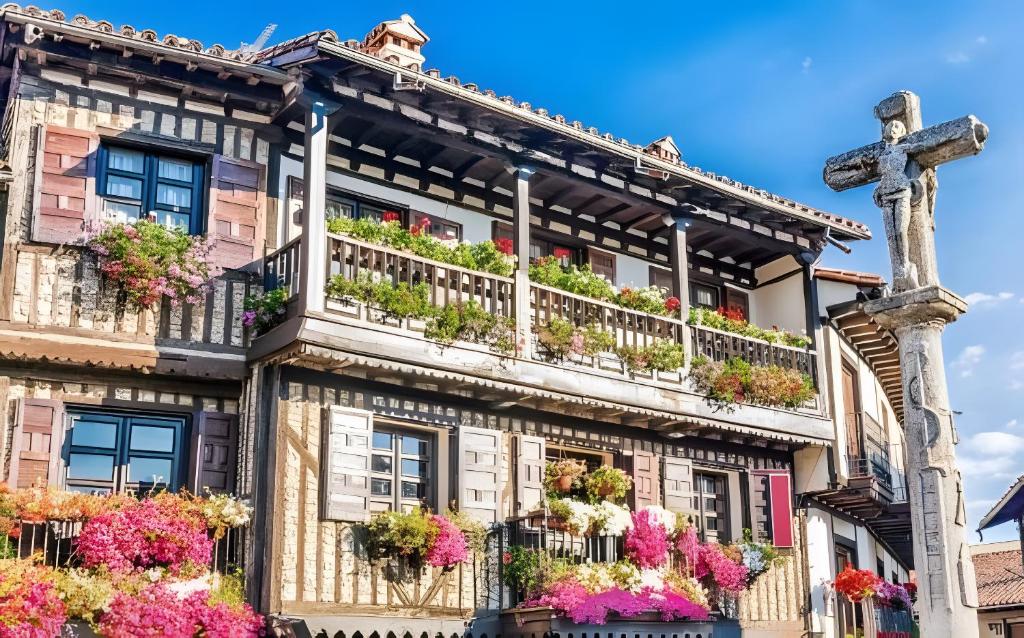 Un edificio antiguo con flores en los balcones y una cruz. en Sierra Quilama, en San Miguel de Valero