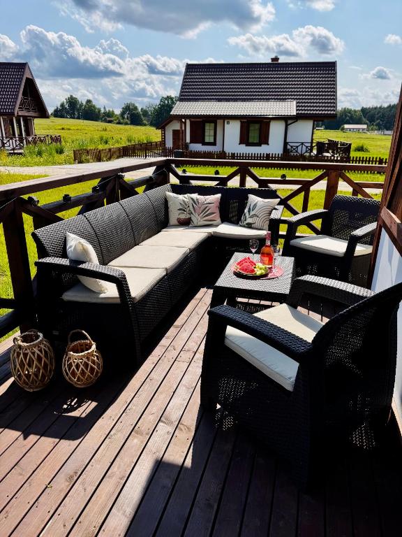 a patio with a couch and chairs on a deck at Warmia Domek Bukowy in Woryty
