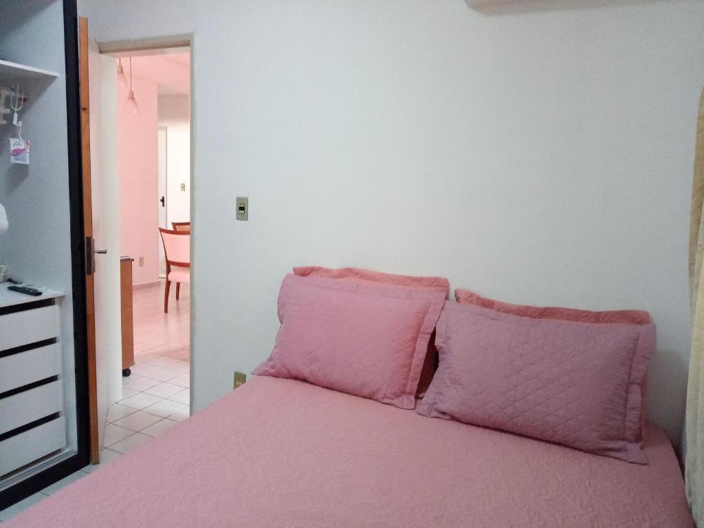 a pink bed with pink pillows in a room at Ap confortável e Aconchegante in Petrolina