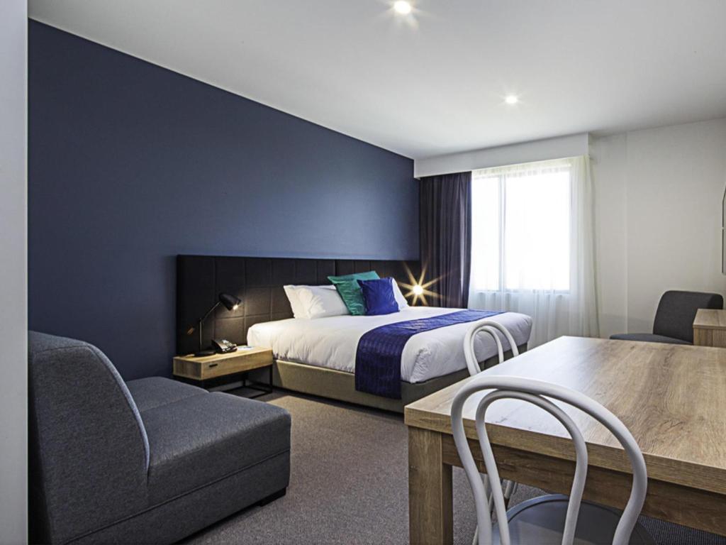 a hotel room with a bed and a table and chairs at Mantra MacArthur Hotel in Canberra