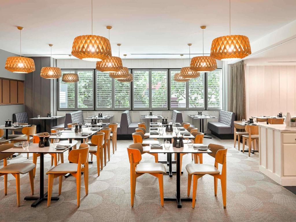 a restaurant with tables and chairs and chandeliers at Mantra on Russell in Melbourne