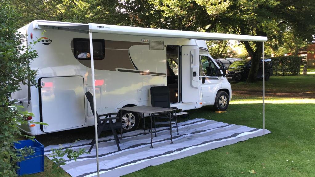 a white camper with a table and a tent at Caravan Tiny House Base Camp Granada Camping in Dúrcal
