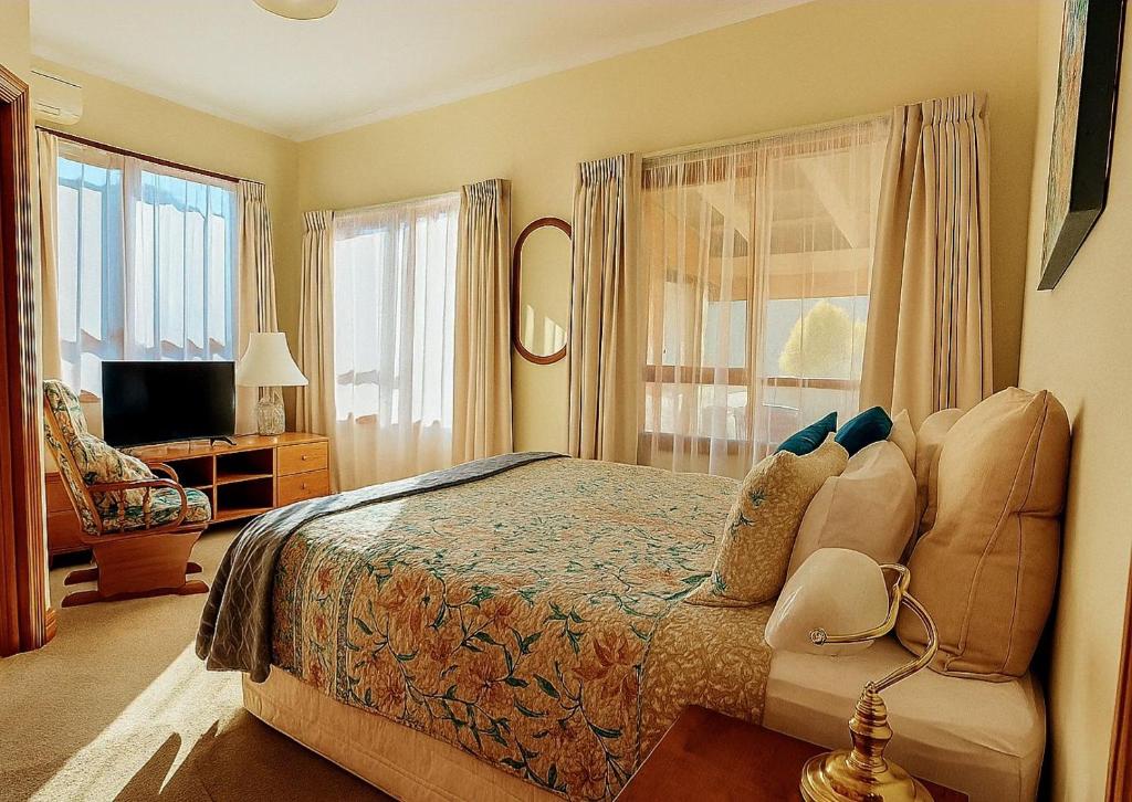 a bedroom with a bed and a chair and a television at Hamlet Downs Country Accommodation in Fentonbury