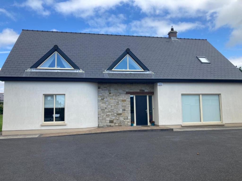 a white house with a black roof and windows at Circular Road Comfort - UHG & University Access in Galway