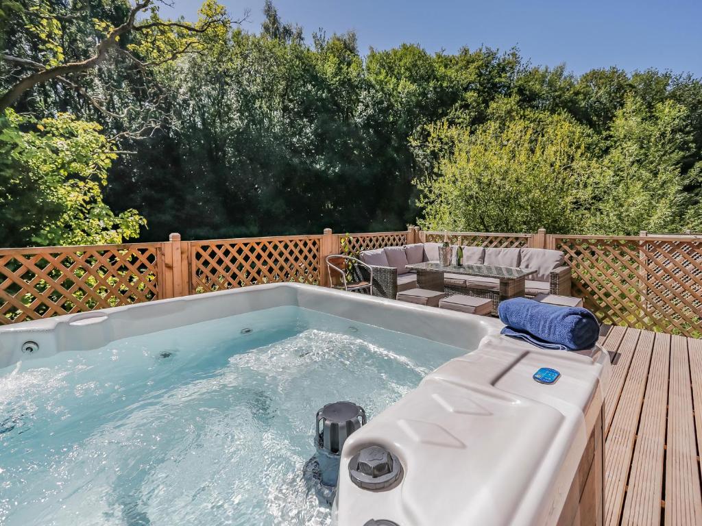 a large hot tub on a deck with a table and chairs at Waterside Lodge in Elland