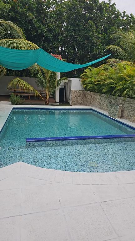een groot zwembad met een blauwe parasol eroverheen bij Villas Campos Monterrico in El Banco