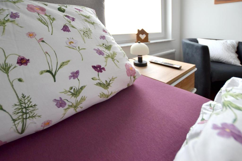 a bed with a pillow with flowers on it at Wohnen bei Gerlis in Burbach