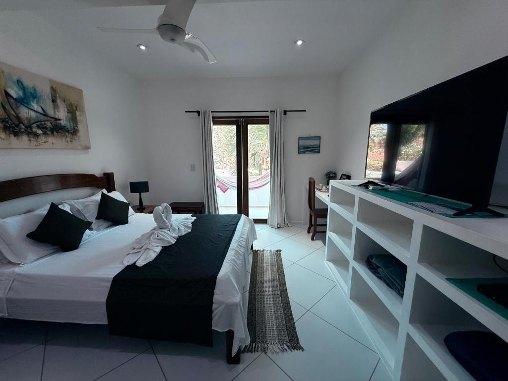 a bedroom with a bed and a television in a room at Pousada Caminho da Praia in Jericoacoara