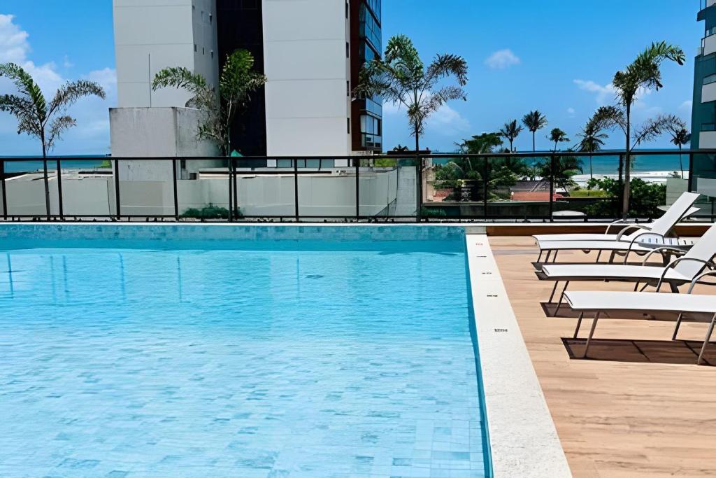 a swimming pool with chaise lounges and chairs at Apartamento na Praia dos Milionários - 100M do Mar in Cururupe