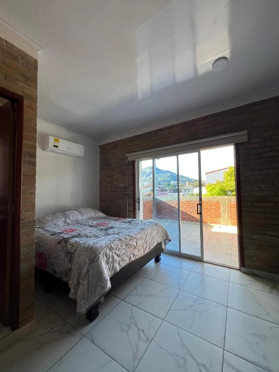 ein Schlafzimmer mit einem Bett und einer Glasschiebetür in der Unterkunft The Cayetano House in Cali