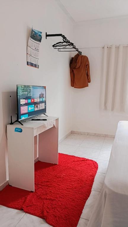 a room with a desk with a computer on a red rug at Família Freitas in Ananindeua