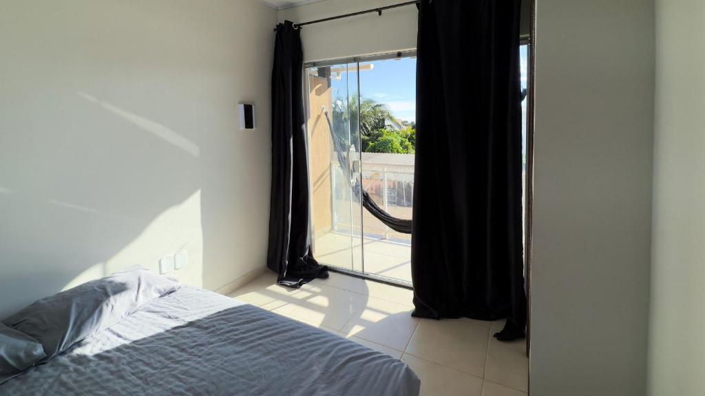 a bedroom with a bed and a window with a view at Duplex em Itaúna 4min da Praia que ocorre o WSL, 1min da pista de skate do LS, pracinha com parque infantil, quadra de futebol, tudo isso a 1 min da duplex, perto do comércio, wi-fi super rápido, estacionamento gratuito, monitoramento 24hrs in Saquarema