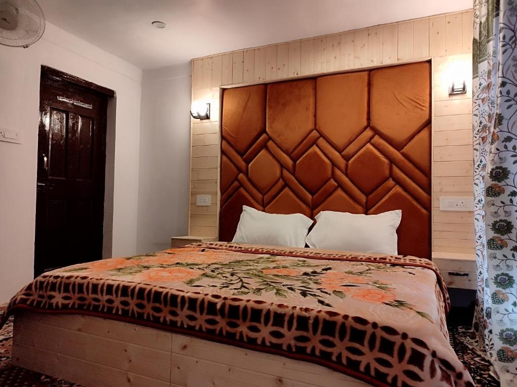 a bedroom with a large bed with a wooden headboard at Residence Inn Home Stay in Pahalgām