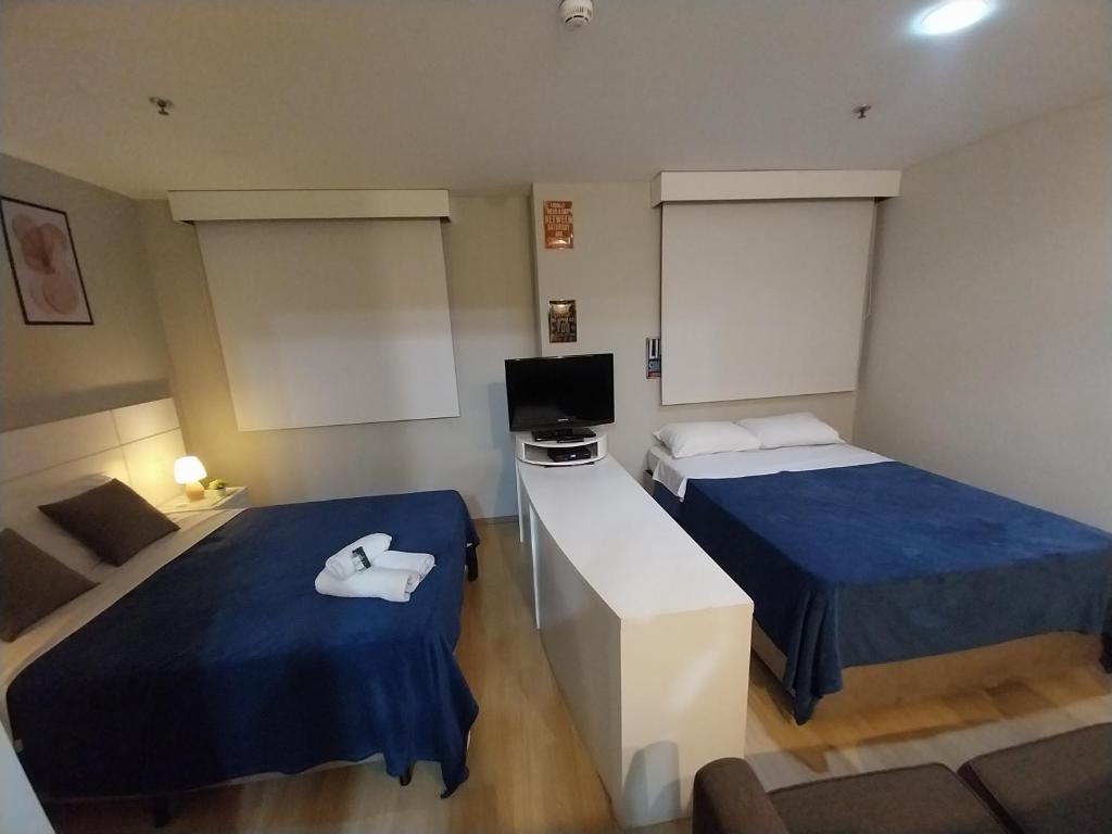 a small room with two beds and a television at Flat Wyndham2 Paulista com estacionamento in Sao Paulo
