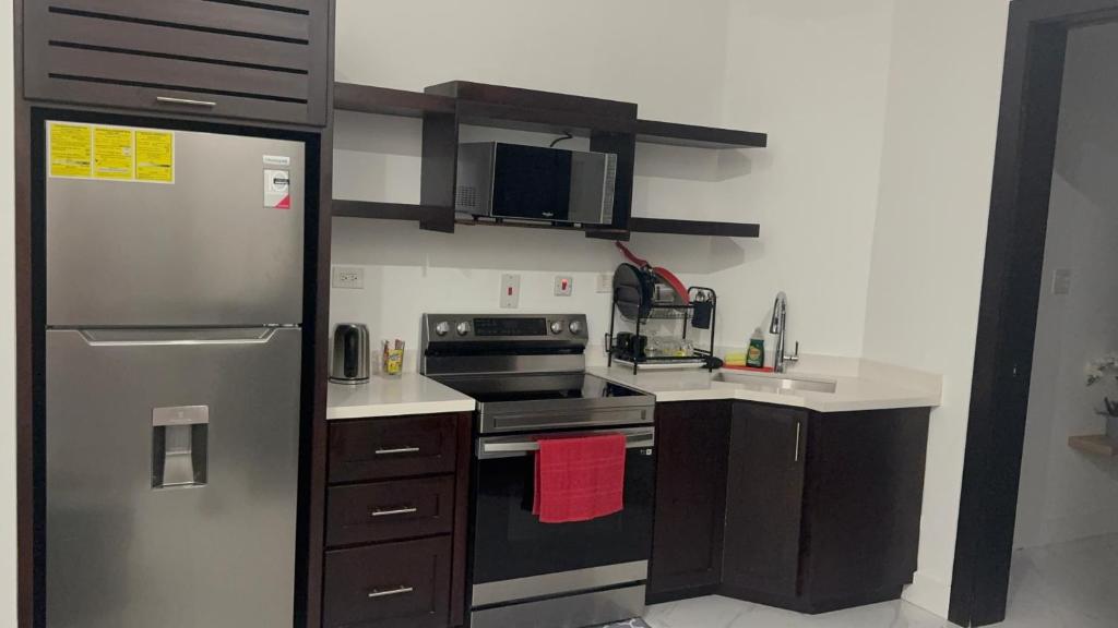 a kitchen with a refrigerator and a stove top oven at City Abode Kingston Jamaica in Kingston