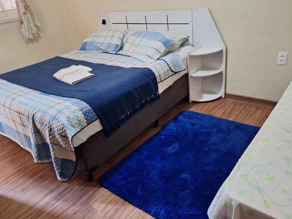 a bedroom with a bed and a blue rug at Pousada Essenza lindoía in Águas de Lindóia