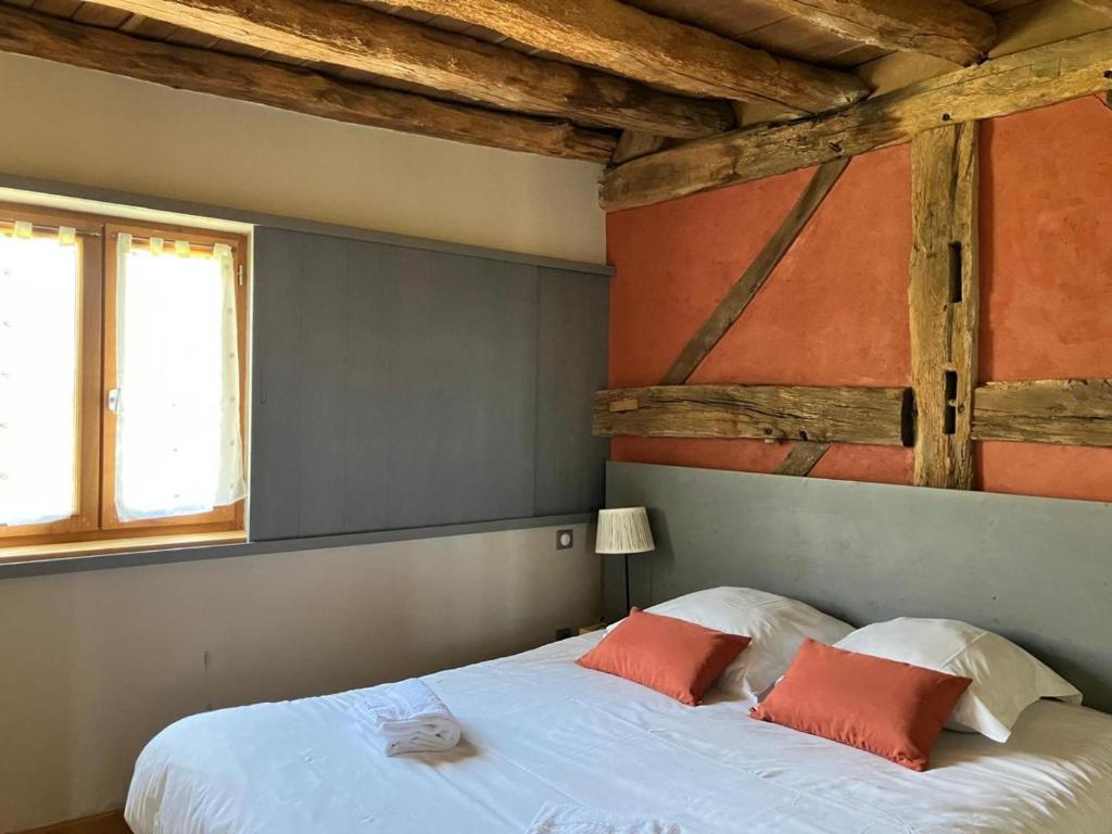 a bedroom with a white bed with two orange pillows at Gîte La Huzarde: Havre de paix en nature, Allier - FR-1-489-599 in La Faye