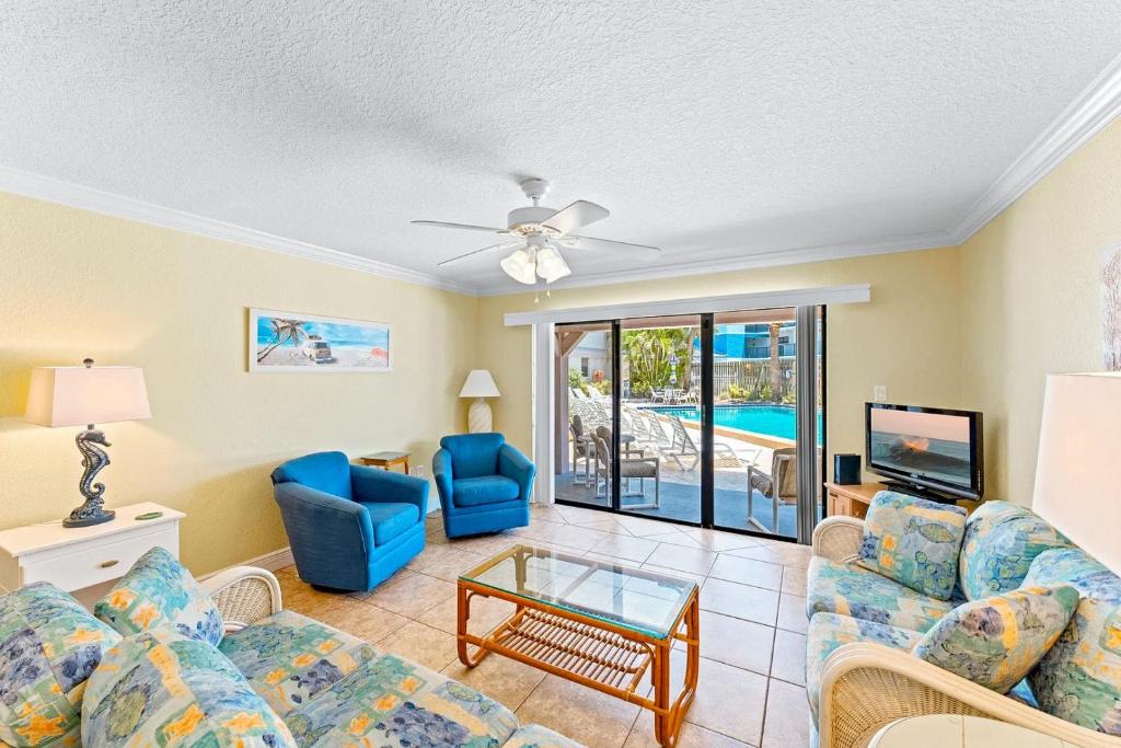Una sala de estar con un sofá y sillas y un televisor. en Ola Grande by Happy Palm Stays, en Cocoa Beach