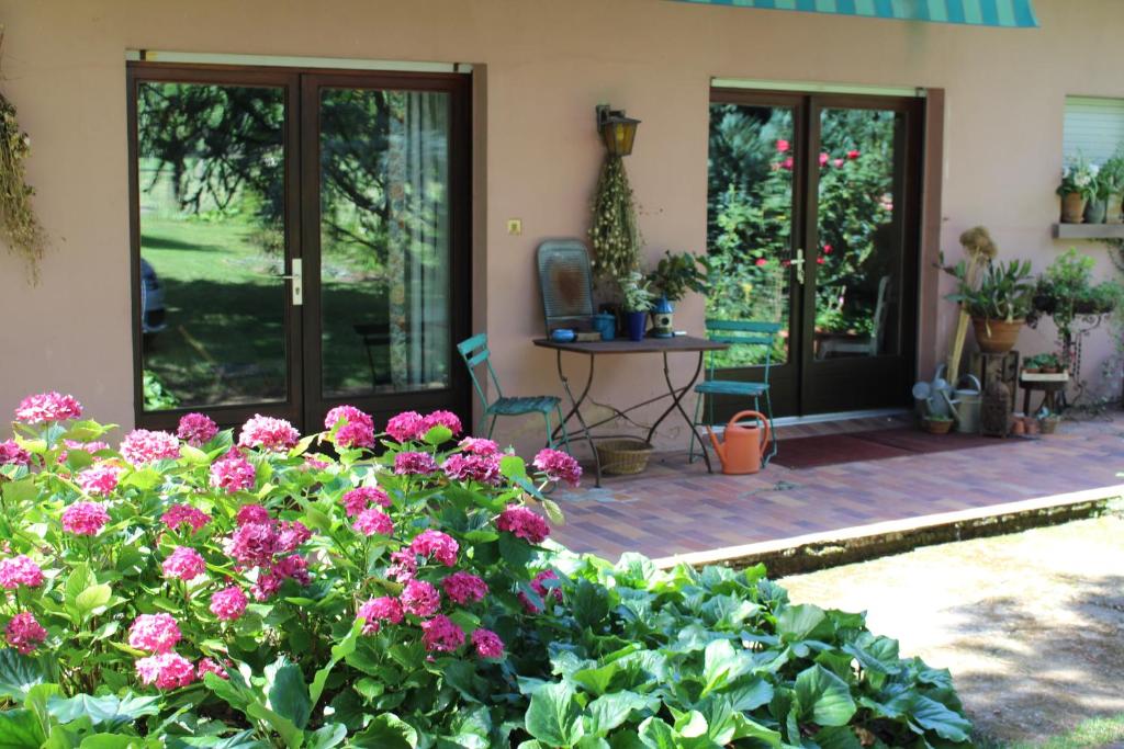 une maison avec une terrasse fleurie et une table dans l'établissement Dans le Jardin de Marie, à Bouxwiller