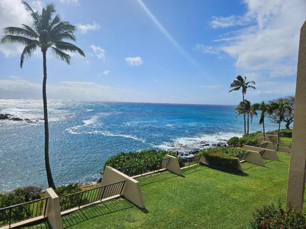 a view of the ocean with benches and palm trees at Napili Point C22 · NP C22 Oceanfront Views from 2BD West Maui Co in Lahaina