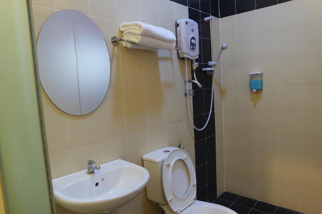 a bathroom with a toilet, sink and mirror at Hotel Ideal Senawang in Seremban