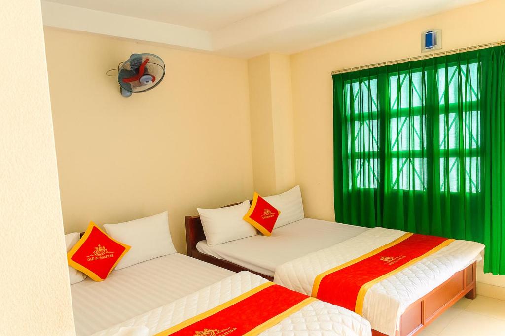 two beds in a room with a green window at Mây Trắng Hotel in Ho Chi Minh City