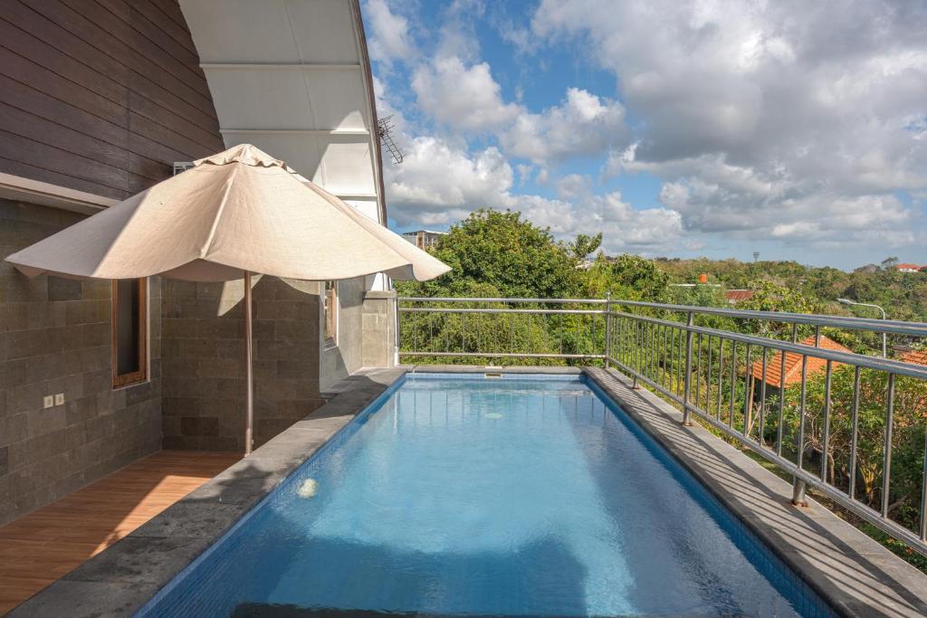 a swimming pool on a balcony with an umbrella at Blue Oceana Villa in Nusa Dua