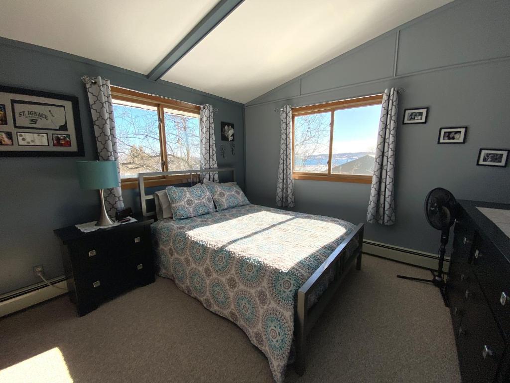 a bedroom with a bed and two windows at Hazel House in Saint Ignace