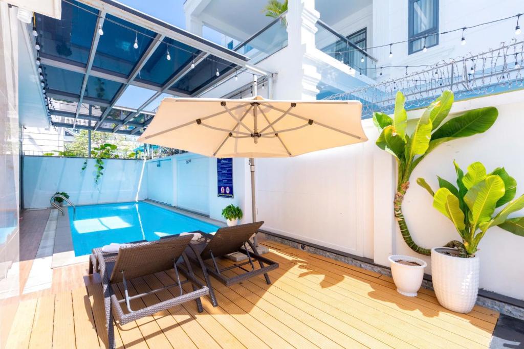 un patio avec une table, des chaises et un parasol dans l'établissement B2-11 Villa Long Cung, à Vung Tau