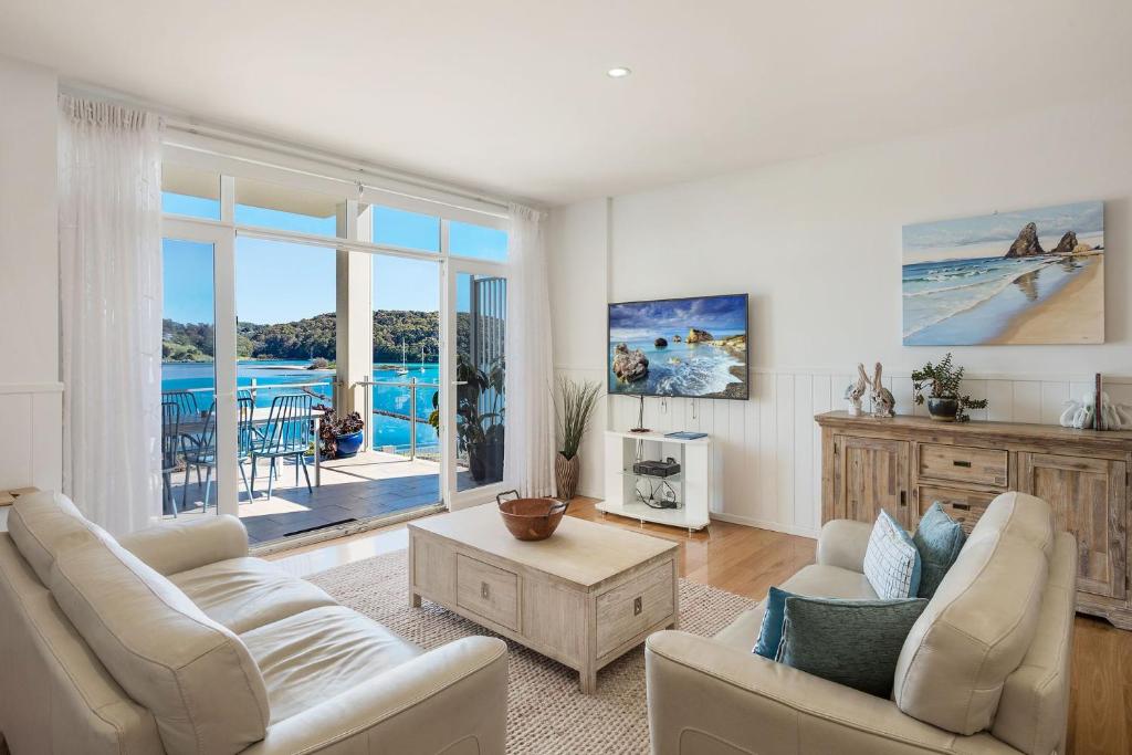 a living room with white furniture and a view of the ocean at Wharf Apartment Unit 5 in Narooma